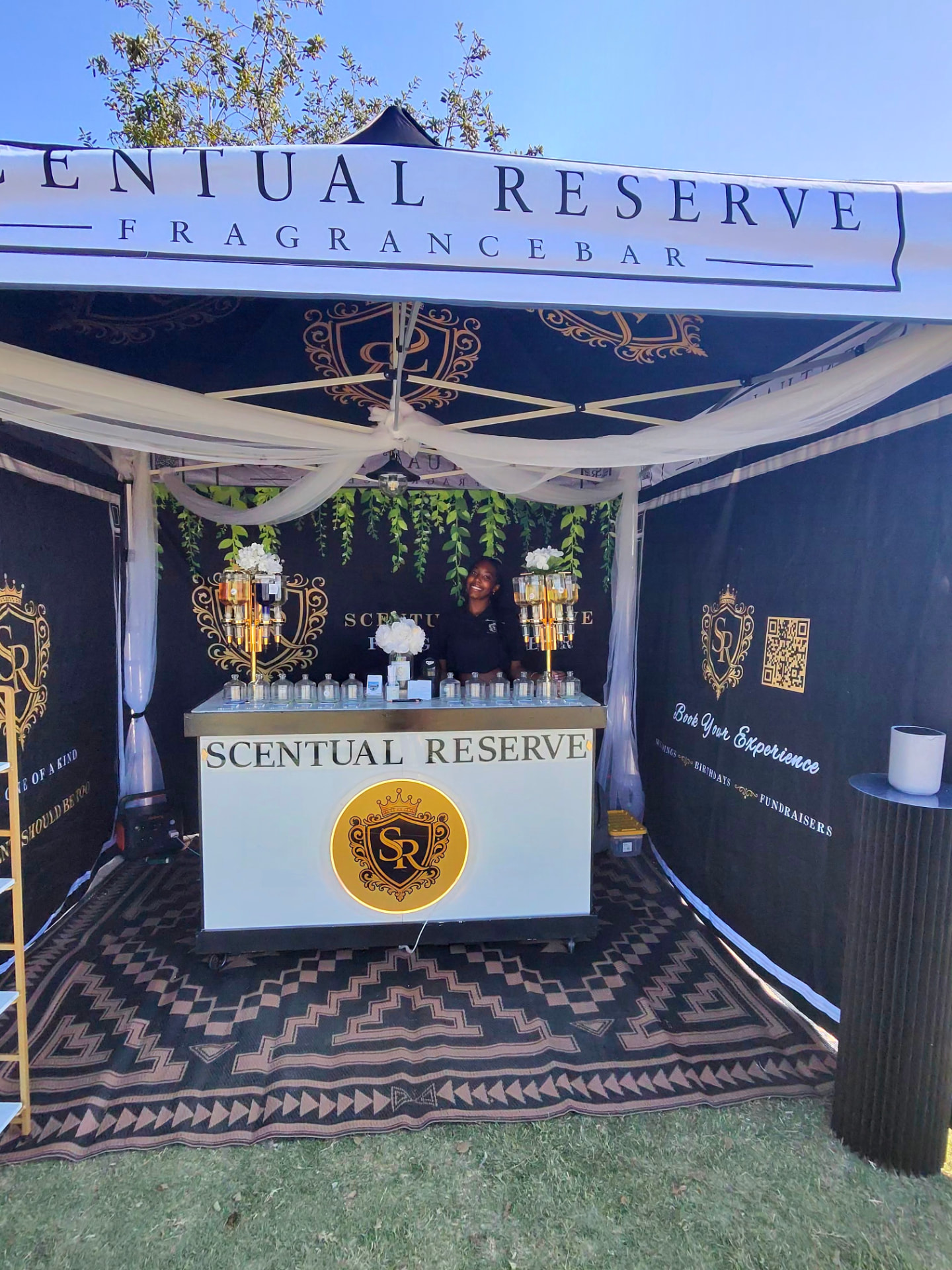 Scentual Reserve canopy booth with black-and-gold backdrop and illuminated crest