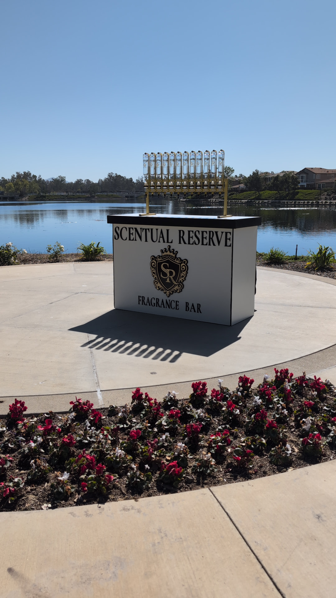 Scentual Reserve fragrance bar set beside a lake with gold dispensers